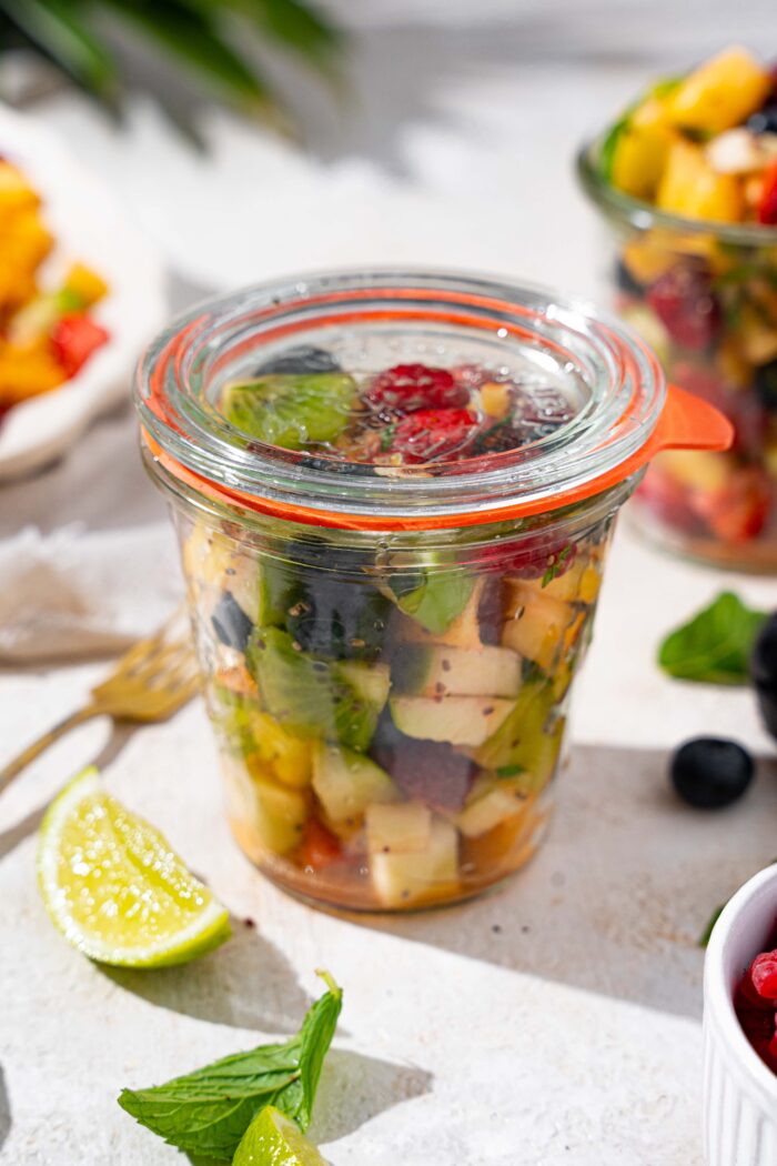 glass jar with an airtight lid filled with fresh fruit salad recipe with mint and lime for meal prep