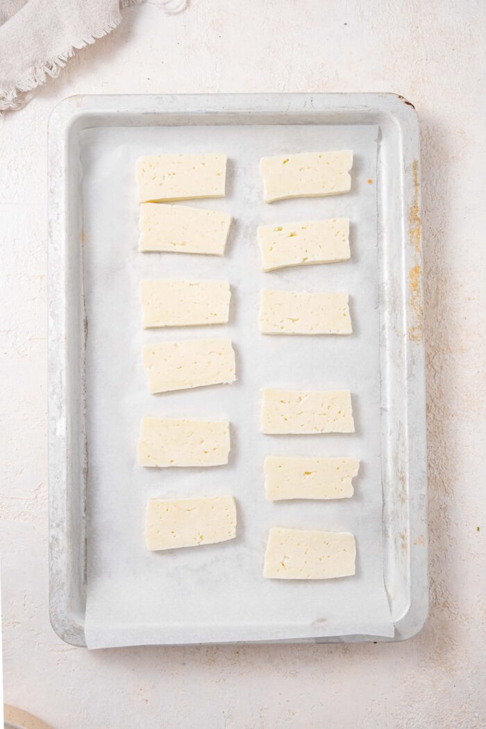 tofu sliced and laid out on a lined baking sheet