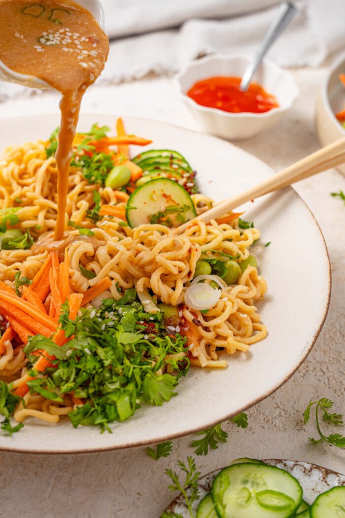 Sesame sauce being poured over cold sesame noodles.