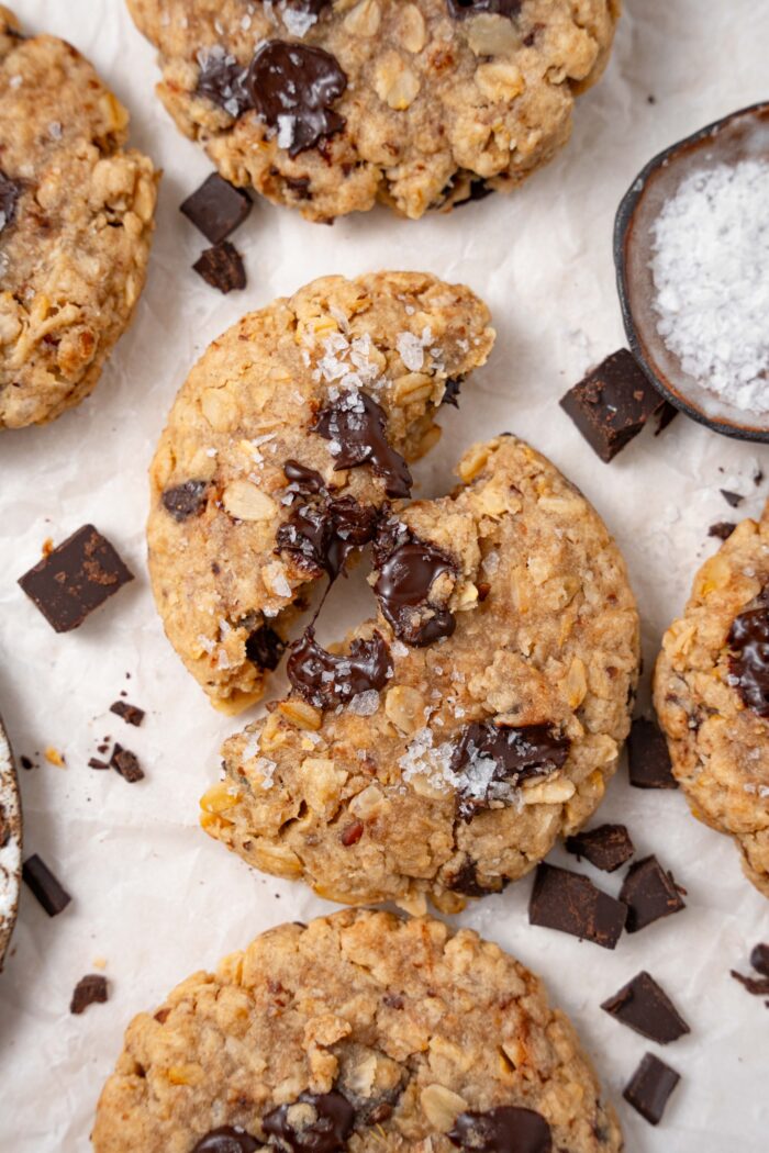 healthy tahini chocolate chip cookie broken in half and surrounded by other cookies