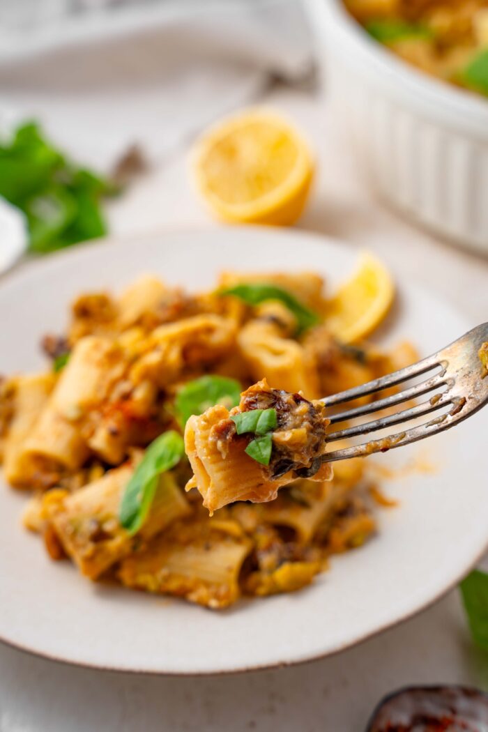 Close-up shot of a fork with some zucchini lemon pasta and fresh basil.