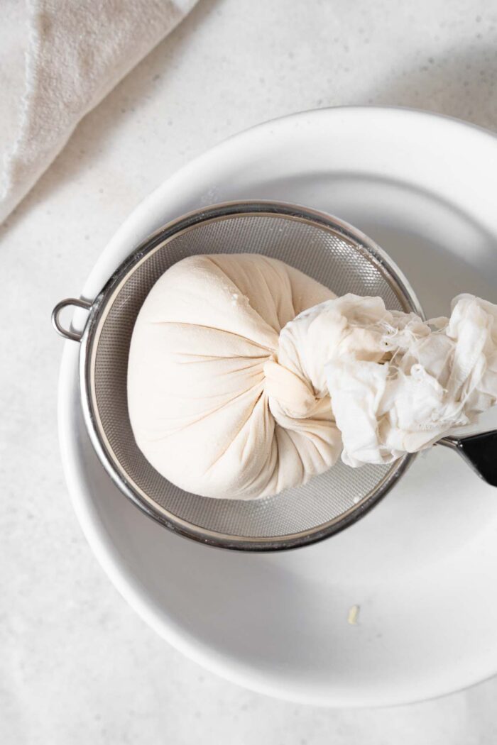 Soy curds twisted into a tight ball using cheesecloth.