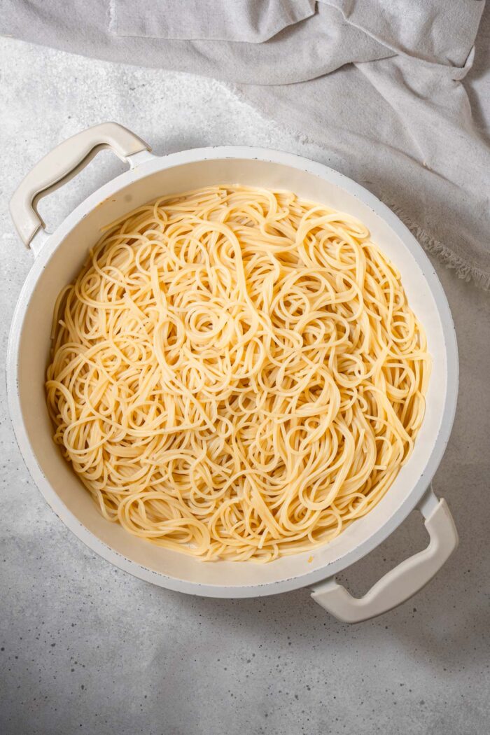 Cooked spaghetti in a white non-stick pot.