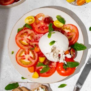 Vegan burrata served with heirloom tomatoes, basil, and bread.