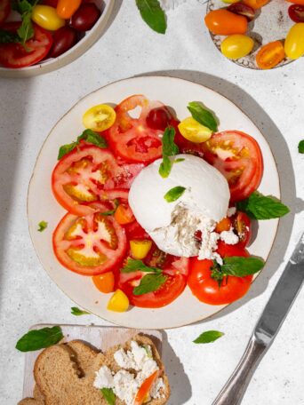 Vegan burrata served with heirloom tomatoes, basil, and bread.