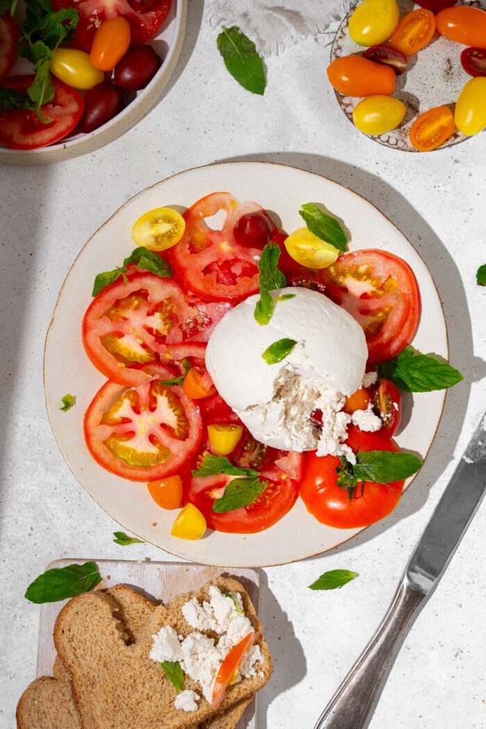Vegan burrata served with heirloom tomatoes, basil, and bread.