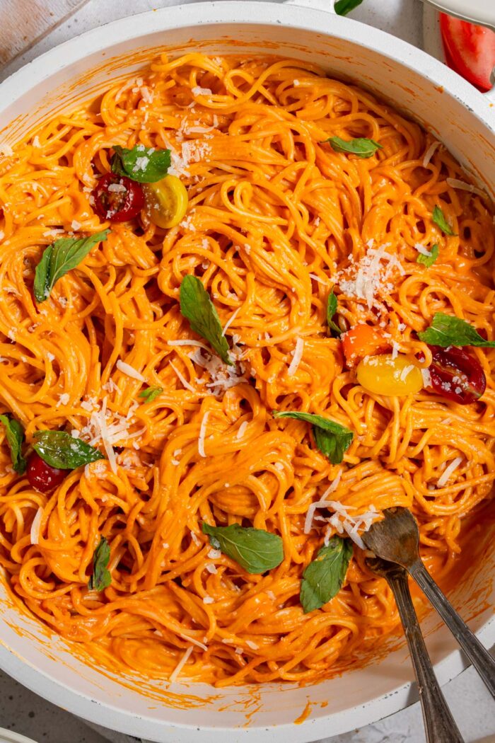 Roasted red bell pepper sauce mixed with pasta and topped with basil and vegan parm.