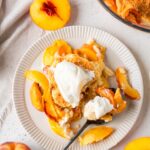 A serving of vegan peach cobbler with ice cream on a plate.