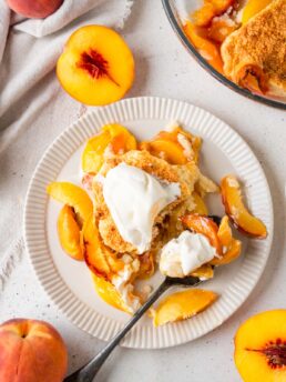 A serving of vegan peach cobbler with ice cream on a plate.