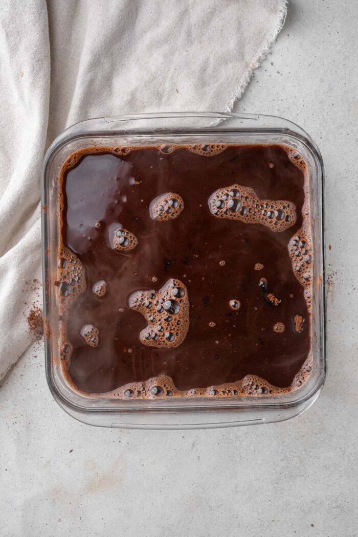 Boiling water coverning the cocoa powder layer of the pudding cake.
