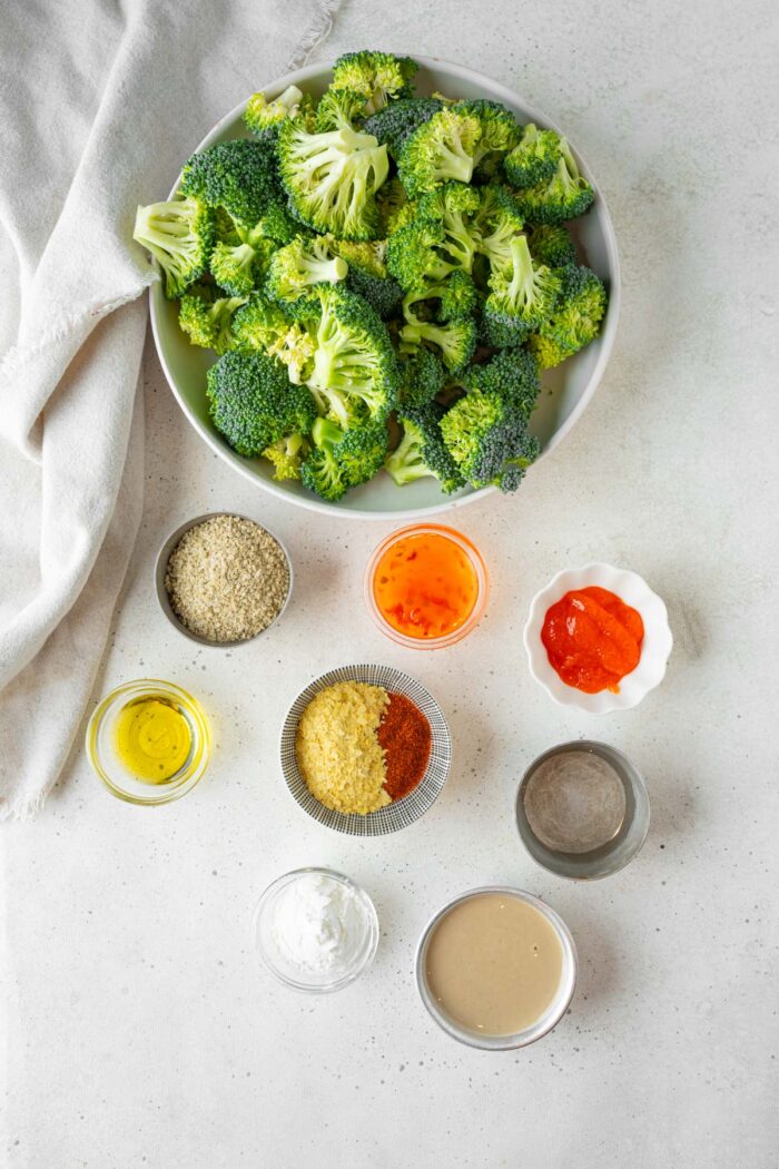 Broccoli, spices, and sauce ingredients laid out on a white background.