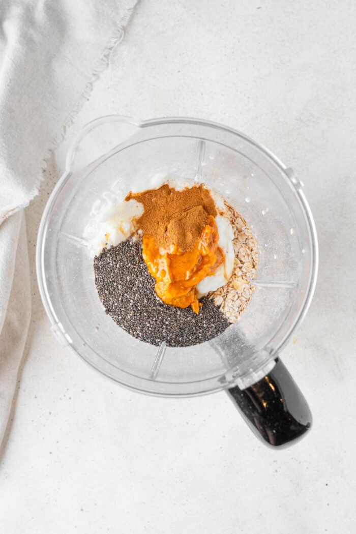 Pumpkin, chia, vegan milk and yogurt, maple syrup, and spices in a blender.