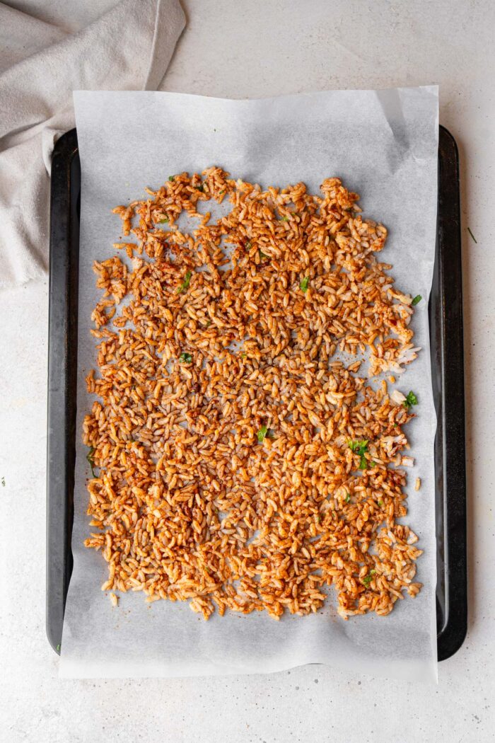 Rice mixed up with the seasonings and spread on the sheet pan.