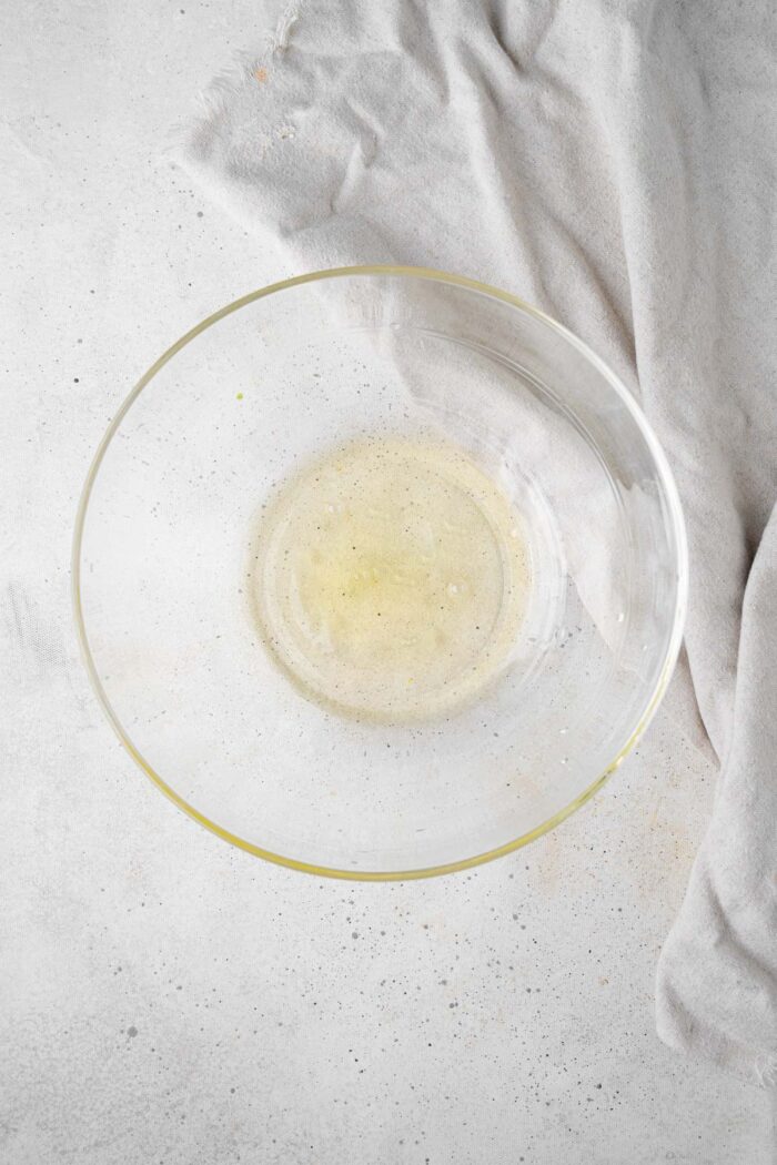 Aquafaba and cream of tartar in a glass mixing bowl.