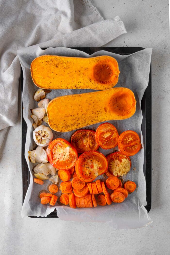 Roasted vegetables on a sheet pan, including squash and carrots.