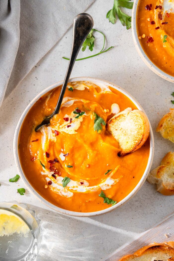 Butternute squash carrot soup, served with bread and fresh herbs.