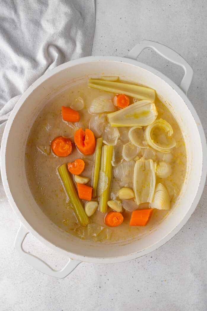 Cooked vegetables in a white soup pot.