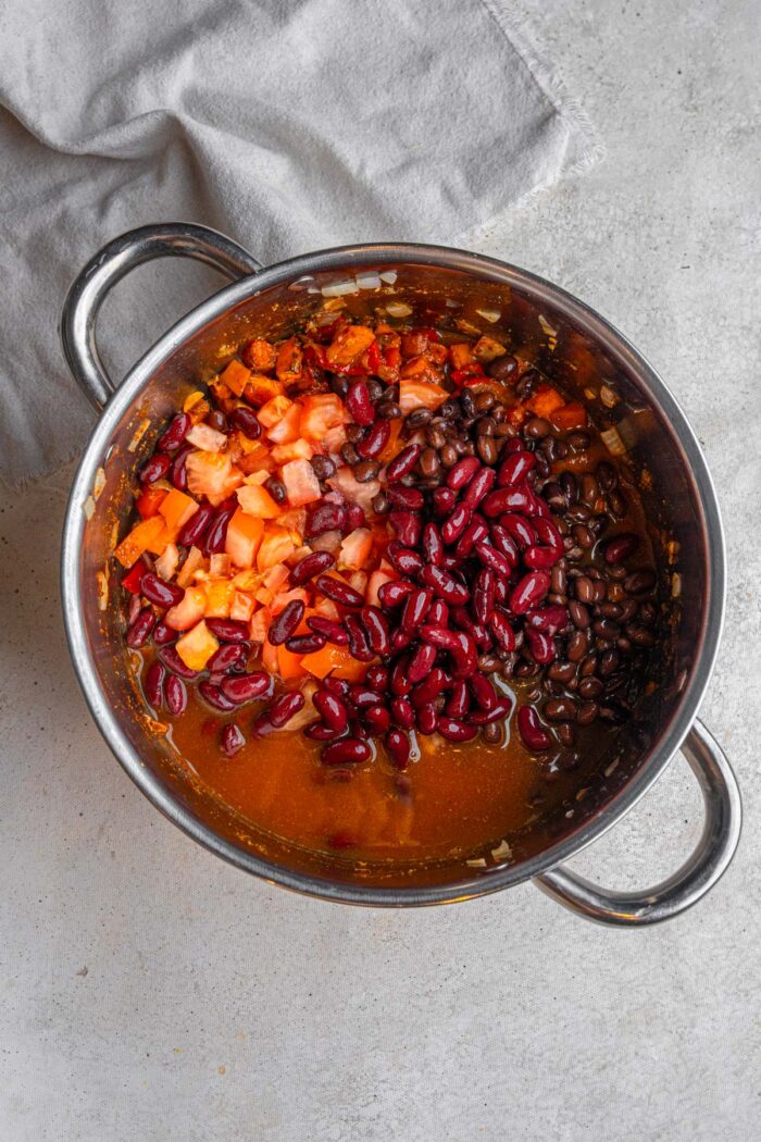 Red kidney beans and canned diced tomatoes added to the pot with vegetables and spices.