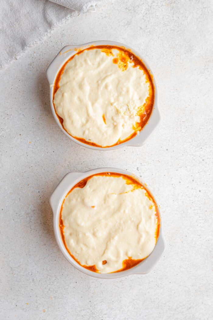 The cornbread mixture spooned on top of the chili in ramekins.