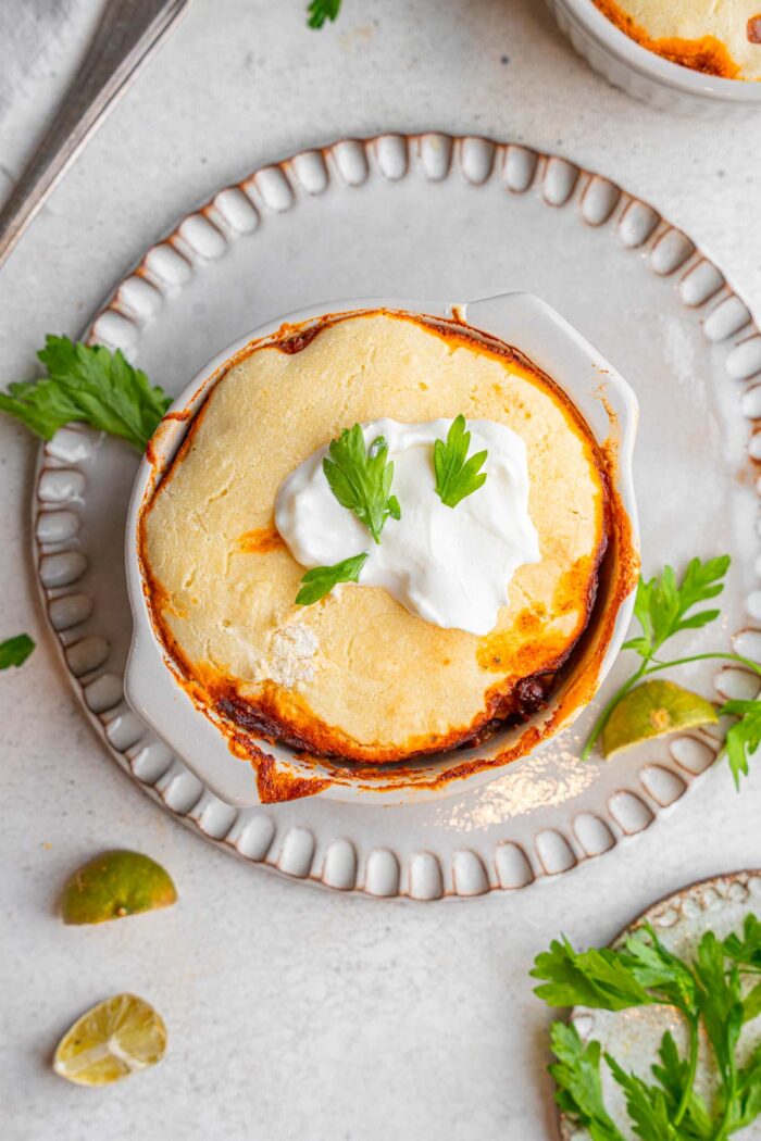 A top-down shot of a ramekin with baked vegan chili and cornbread crust.