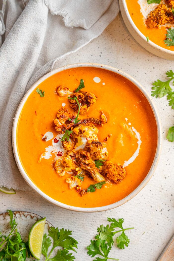 Sweet potato cauliflower soup served with roasted cauliflower florets, parsley, and a drizzle of coconut milk.