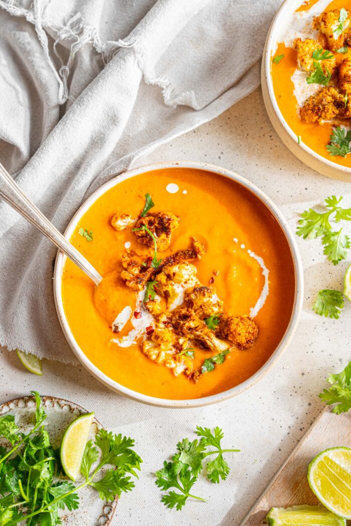 Sweet Potato Cauliflower Soup served in a white ceramic bowl with grilled cauliflower.