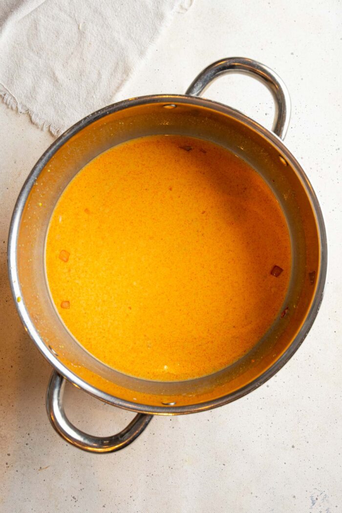 Red curry paste, coconut milk, and vegetable broth added to the pot.