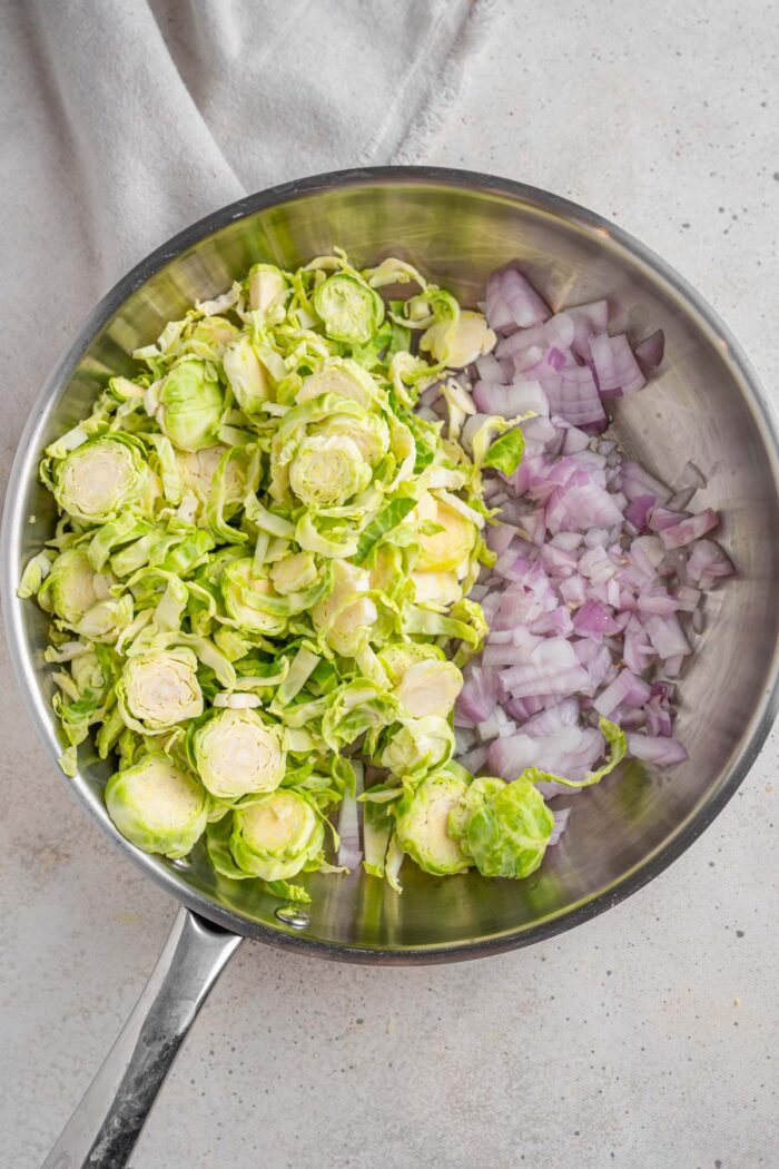 Shredded Brussels sprouts and red onions in a steel frying pan.