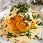 Title image: whole roasted cauliflower with tahini and herb salsa on a white platter.