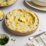 Vegan mashed potatoes served with fresh parsley and vegan buttery with gravy boat visible in the background.