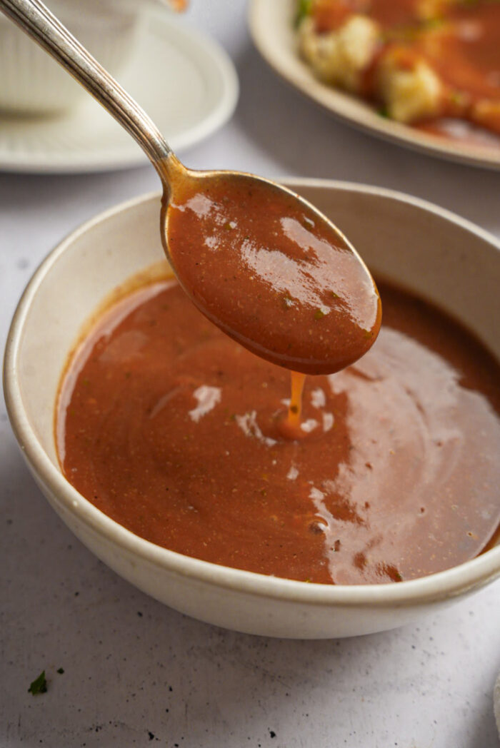 Thick and luscious vegan brown gravy, scooped out of a bowl with a spoon.