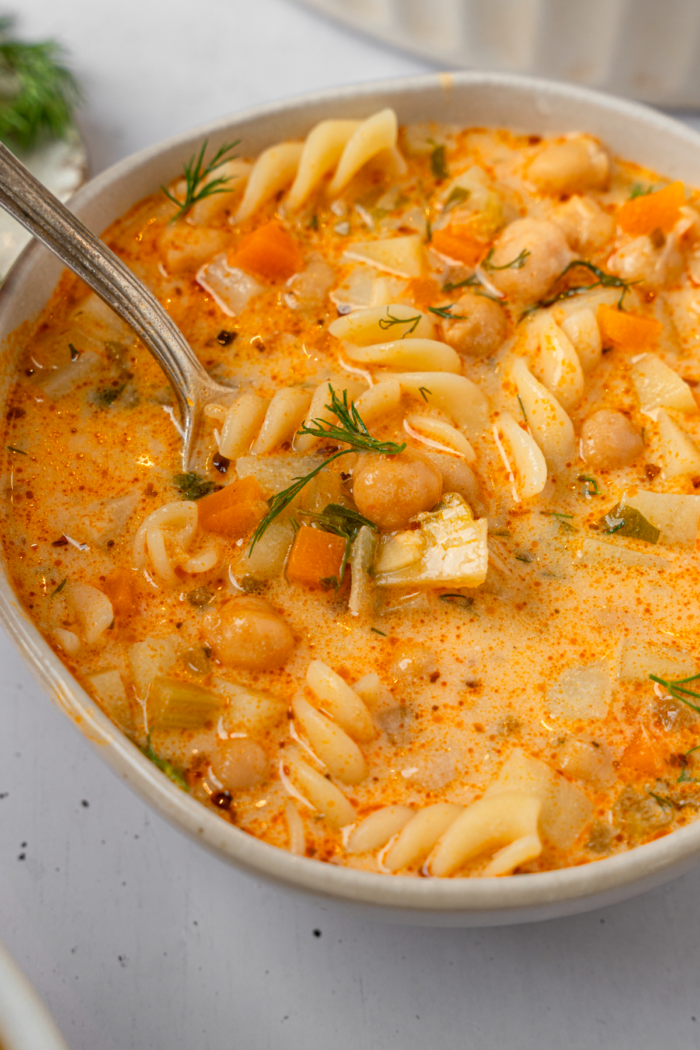 A spoon sticking out of a bowl of soup.