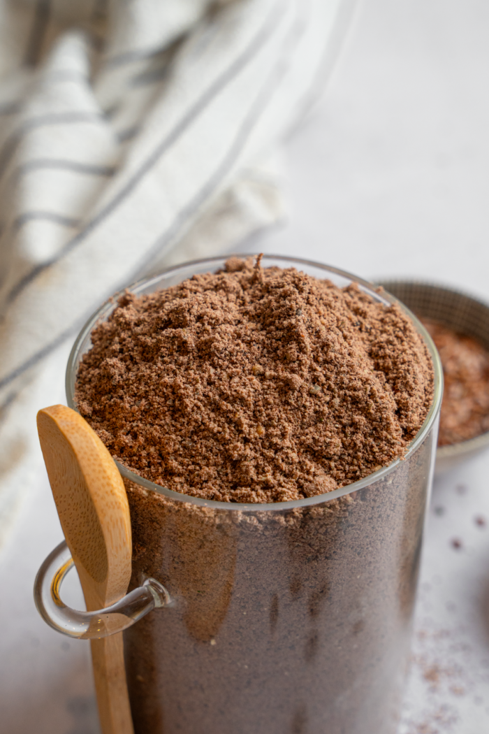 Homemade chocolate protein powder in a glass container.