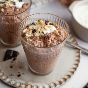 A glass with chocolate chia pudding and a few vegan toppings.