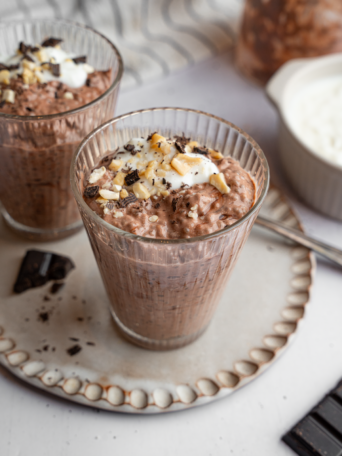 A glass with chocolate chia pudding and a few vegan toppings.