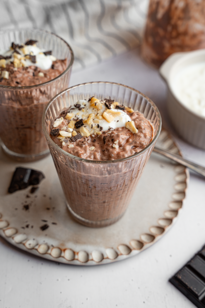 A glass with chocolate chia pudding and a few vegan toppings.