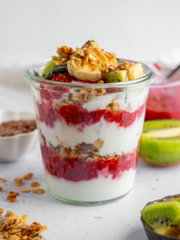 Yogurt parfait with berry syrup and toppings of choice.