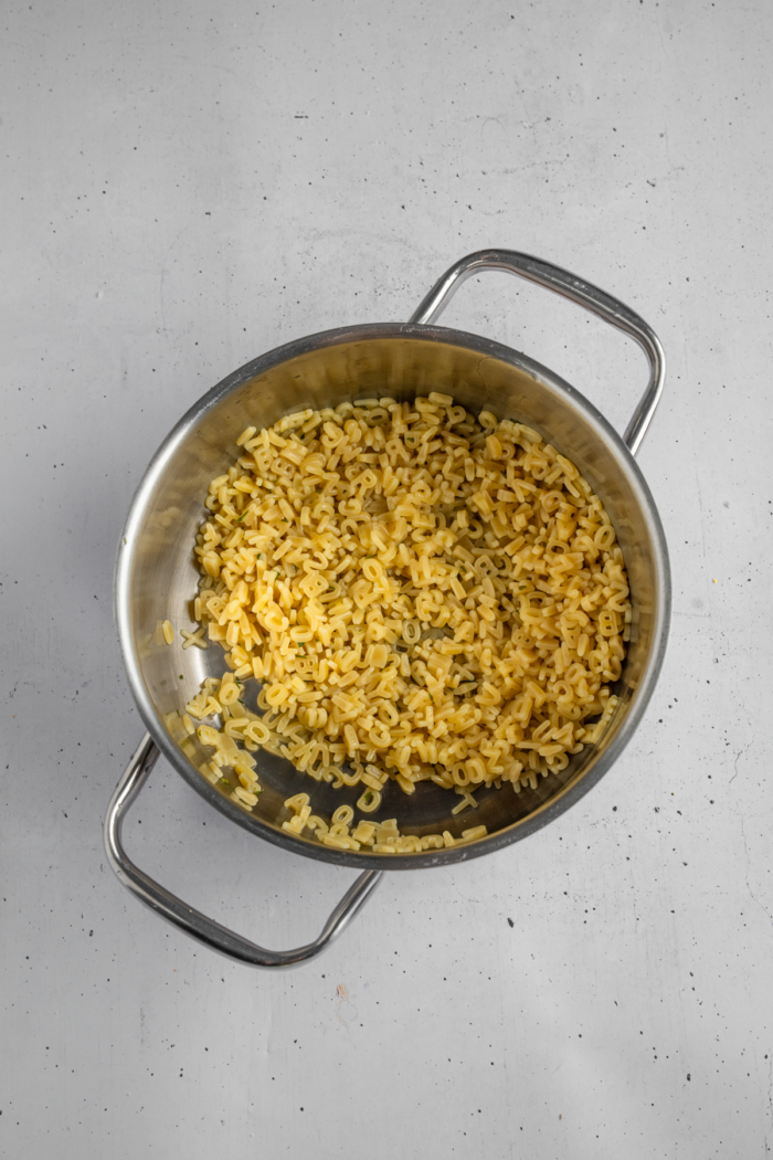 Alphabet pasta cooked in a steel pot.
