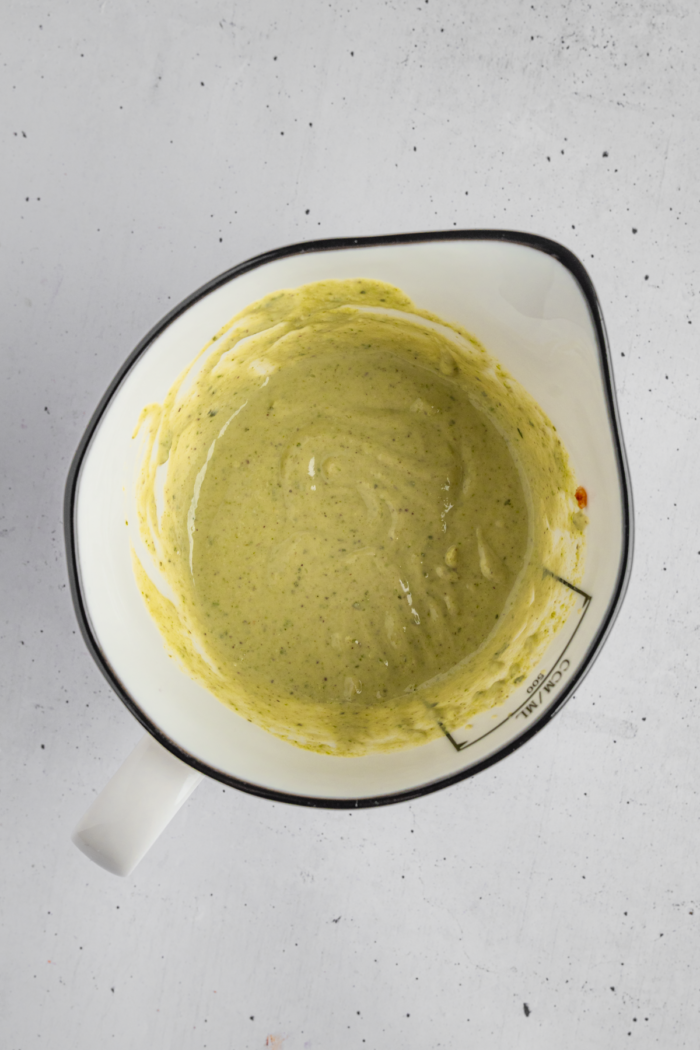 Vegan pesto tahini dressing in a cooking jug.