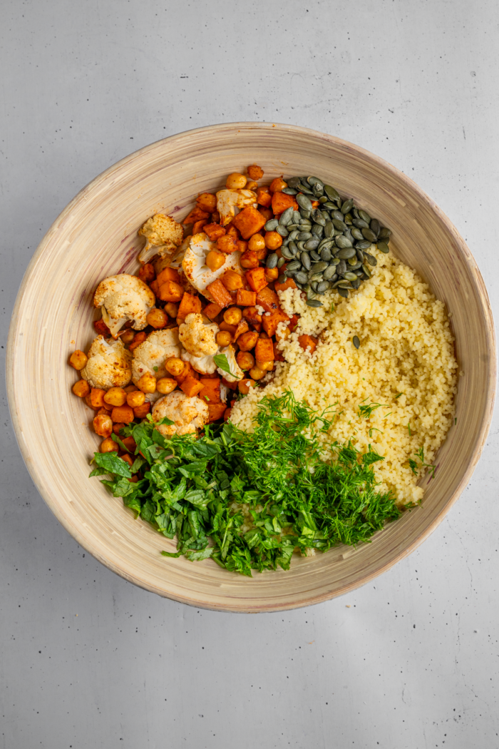 All of the different components for the sweet potato and cauliflower herb couscous salad together in a bowl.