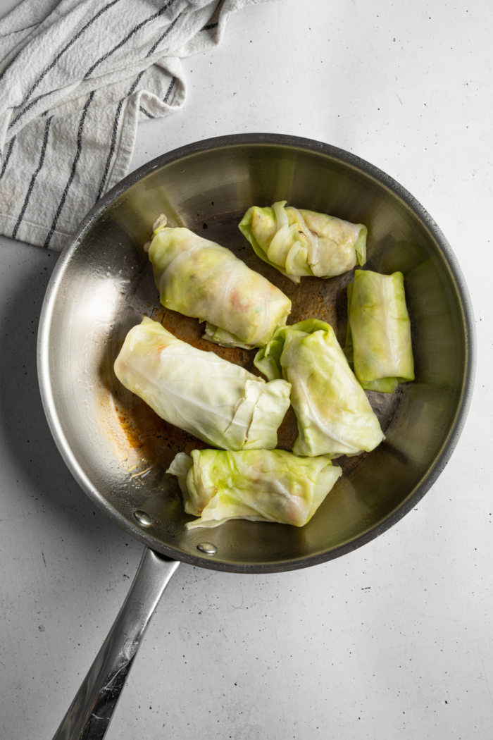 A steel non-stick pan with vegan cabbage wrapped dumplings with tofu.