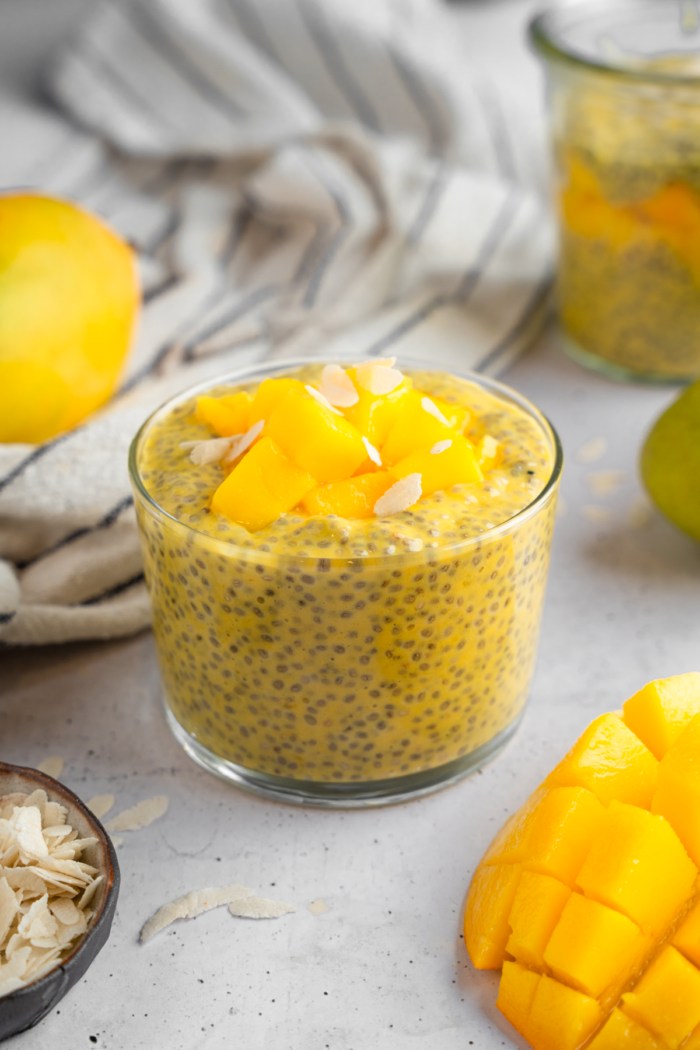 Mango chia pudding served in a glass with chopped mango and coconut shavings.