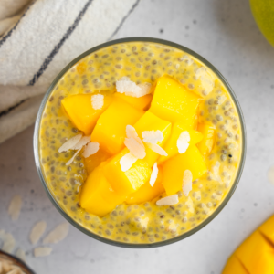 Close up top down shot of mango chia pudding with fresh mango and coconut shavings.