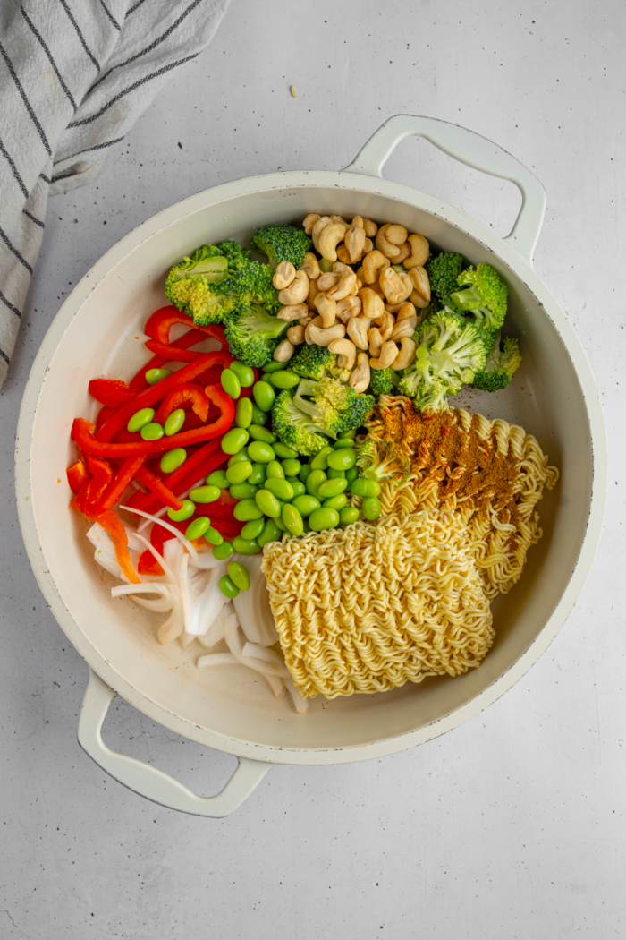 Plain ingredients: veggies, spices, and noodles in a deep pan.