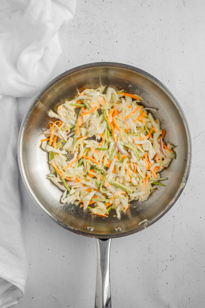 Pre-heated steel frying pan with some vegetable pancake mixture spread evenly.