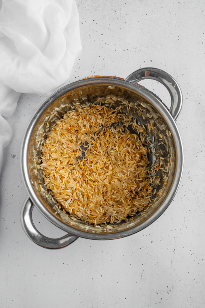 Long grain rice being toasted in a steel pan.
