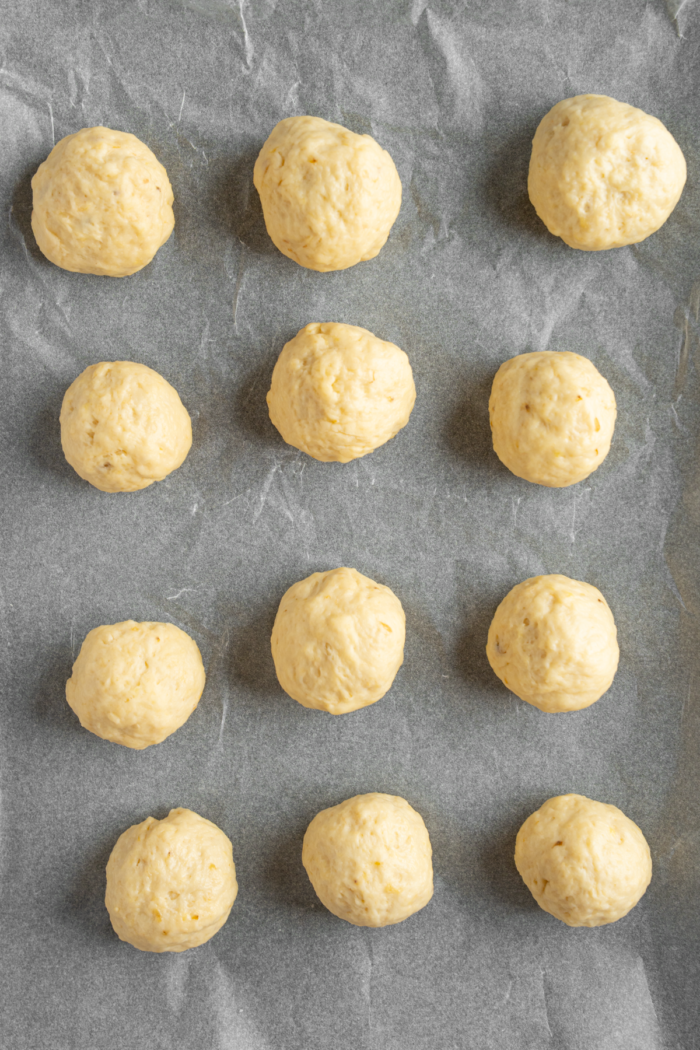 The donut dough rolled into balls and spread on an air fryer tray.