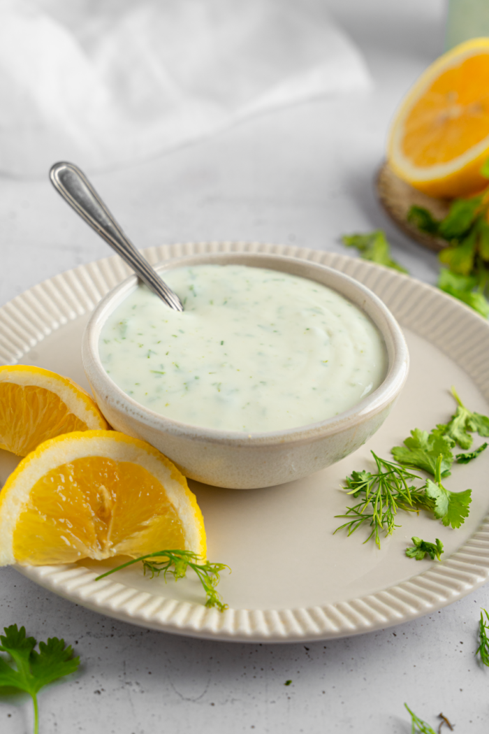 Vegan ranch dressing in a small dipping bowl with a spoon sticking out.