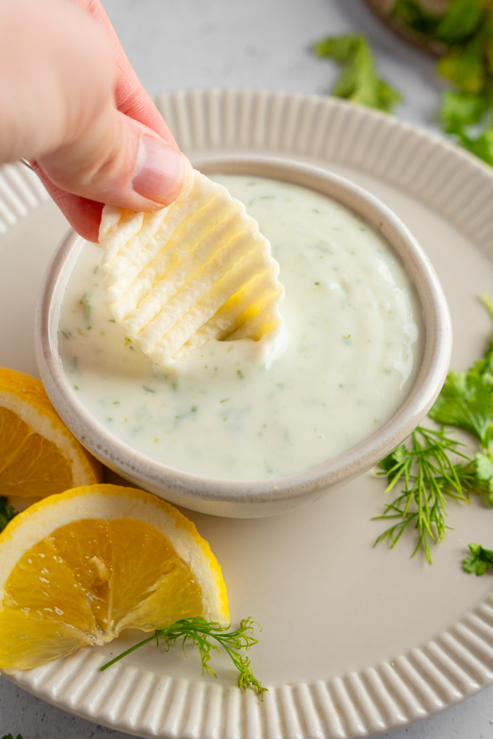 Vegan ranch dressing in a small dipping bowl, with a chip being dipped in.