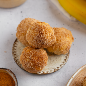 Banana donut holes stacked on a plate.